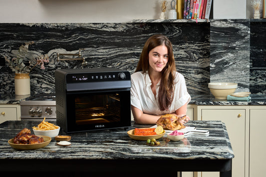 Fridja f77 Super Oven Pro air fryer oven on a marble kitchen counter with roast chicken and side dishes