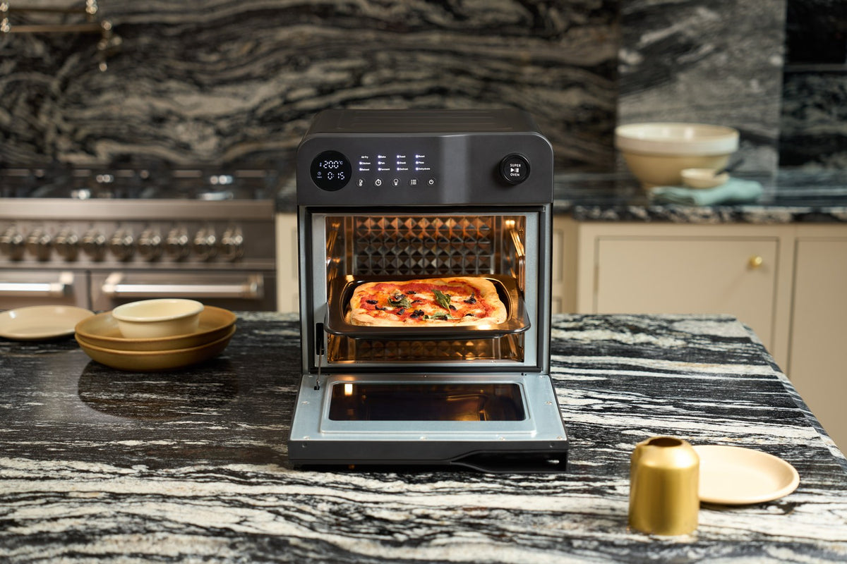Fridja f66 Super Oven air fryer oven with the door open and a freshly baked pizza on the tray, on a marble kitchen counter
