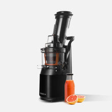 A Fridja f1900 Whole Fruit Juicer in black with a transparent container of orange juice is displayed on a white background. In front, a bottle of nutrient-rich juice and grapefruit halves emphasize the essential vitamins in each glass.