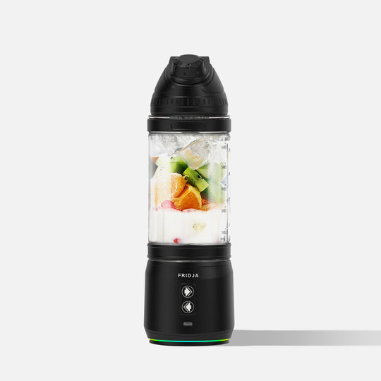 A black Fridja Portable Blender/Juicer Duo - f500 and f2500, filled with ice, yogurt, and orange, kiwi, and banana pieces, stands upright against a plain white background.