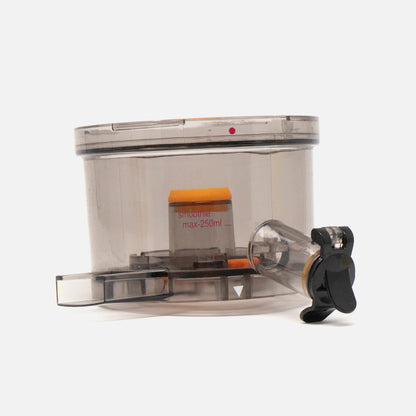 The Fridja f1900 Juicer Bowl, a transparent replacement with measurement markings, black spout, and orange internal part, is displayed against a plain white background.