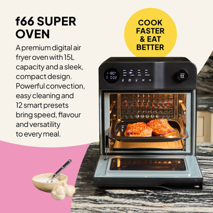 The Fridja f66 Super Oven - 15L Digital Air Fryer Oven in black is open on a kitchen counter, cooking two pieces of salmon. Its display and controls highlight convection features. Nearby sits a bowl of garlic and a spoon.