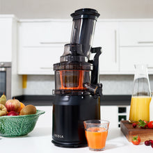 The Fridja Juicer Duo – f1900 Cold Press Juicer & f500 Portable Blender sits on a kitchen counter, pouring fresh orange juice into a glass with mixed fruit, a carafe of juice, and strawberries nearby. White cabinets are in the background.